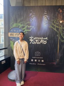 Photo of Cara standing next to the My Neighbour Totoro promotional stand at the Gillian Lynne Theatre